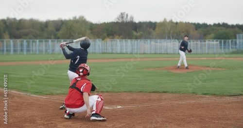College sports, baseball traning game, the pitcher throws the ball towards the batter, batter successfully hits fastball, back view.