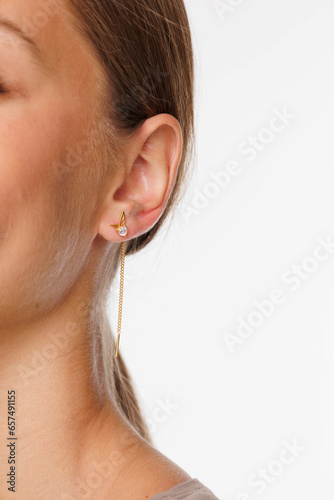 Beautiful young girl with fresh healthy skin. Woman advertise ear-rings. White background. Earrings, ear caffs closeup. Blond european woman with long hair with big lips, pretty smile. Cosmetology photo