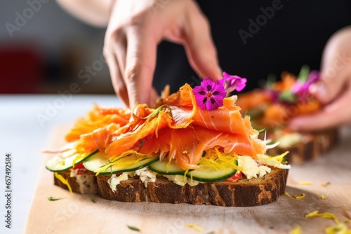 close-up of fingers placing smoked salmon on an open-faced sandwich photo