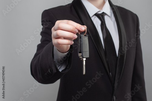 Male hand holding a car key isolated on white. New car concept