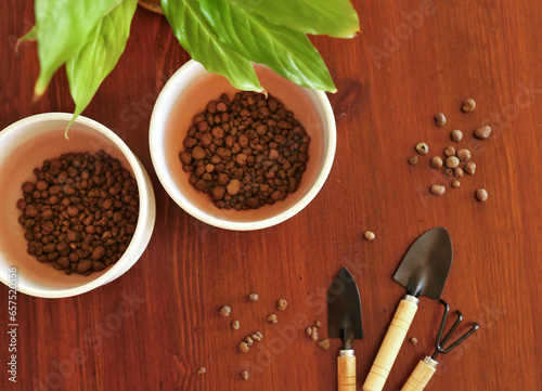 Gardening tools. A shovel, a rake for indoor plants on a brown wooden background. Two white ceramic pots. View from above