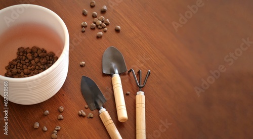 White flower pot, rake, shovels on a wooden table. Gardening tools.	
