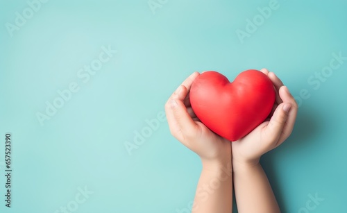 Young women hands holding red heart on blue pastel background.