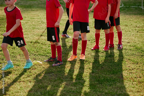 Cropped portrait of little players wearing sport uniform in jersey, shorts and cleats. Kids play football on soccer field. Children's school team.