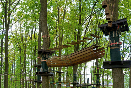 Children's Adventure Park bridges, ropes and stairs designed for beginners in woods among tall trees. Adventure climbing on high wired park.