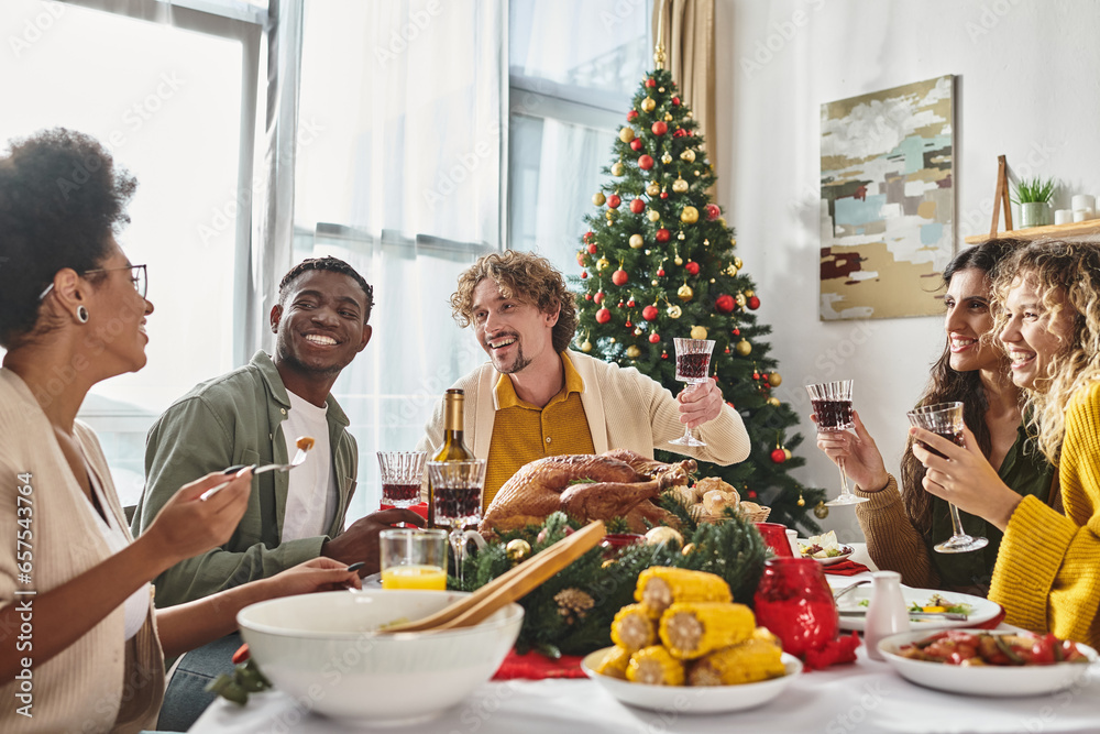 joyous multiethnic family having good time eating festive lunch with raised wine glasses, Christmas