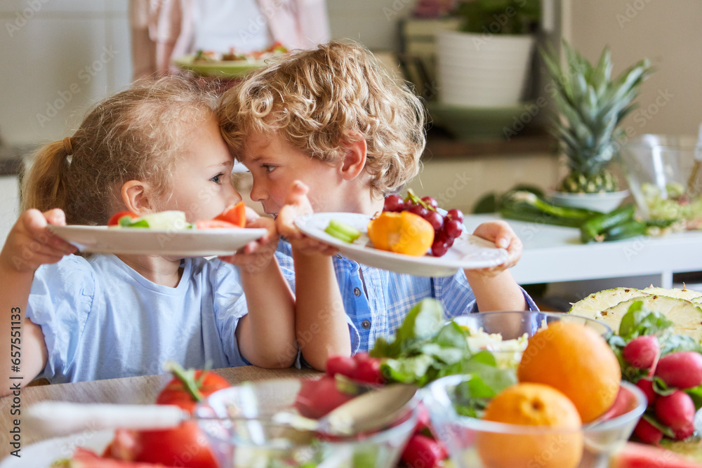 Playful siblings having fun while holding fruit salad plates Playful siblings having fun while holding fruit salad plates