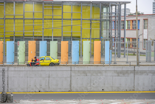 Taxi amarelo e moto com fachada colorida de fundo em Lima.  photo