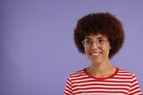 Portrait of happy young woman in eyeglasses on purple background. Space for text