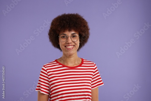 Portrait of happy young woman in eyeglasses on purple background. Space for text © New Africa
