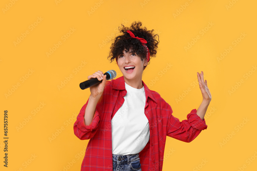 Beautiful young woman with microphone singing on yellow background Beautiful young woman with microphone singing on yellow background