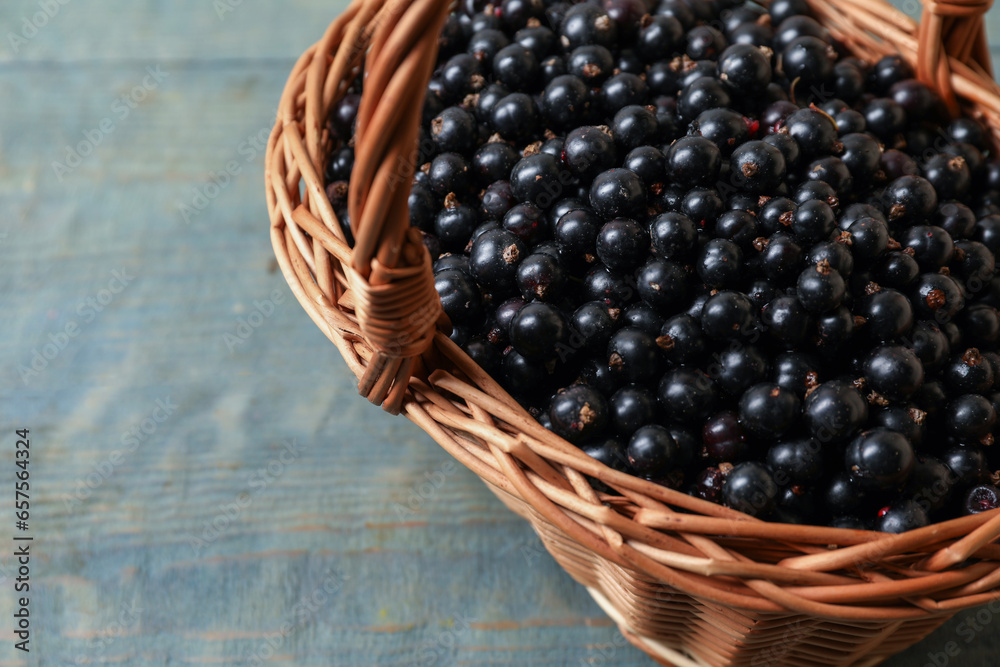Ripe blackcurrants in wicker basket on wooden rustic table, closeup. Space for text Ripe blackcurrants in wicker basket on wooden rustic table, closeup. Space for text