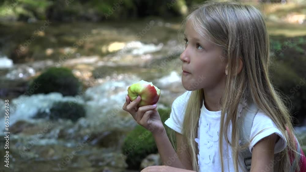 Child Eating Apples by River, Camping Mountains View, Girl Eats Fresh Fruits Outdoor in Nature Child Eating Apples by River, Camping Mountains View, Girl Eats Fresh Fruits Outdoor in Nature