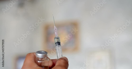 Using syringe suck out of bottle by turning the medicine bottle upside down and slowly pulling the medicine out of the bottle.Syringe with liquid being drawn into syringe.Testosterone. photo