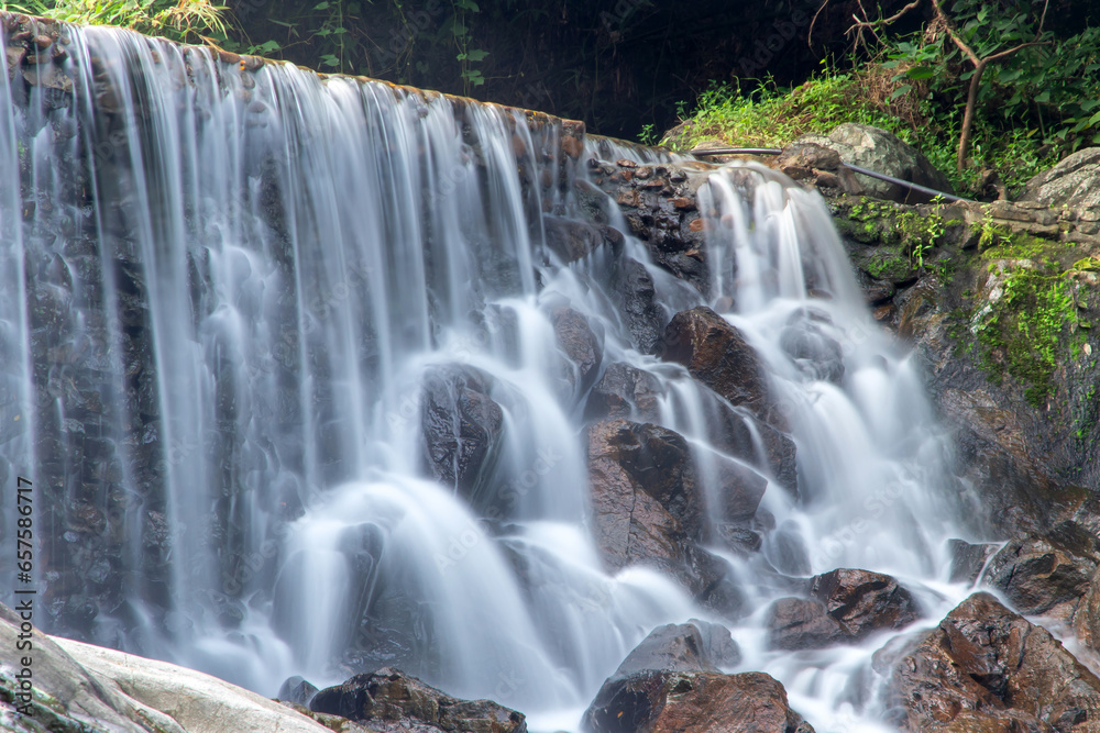 Small waterfall with water splashing and tumbling over the rocks in the forest on a bright sunny,kra-ang waterfall