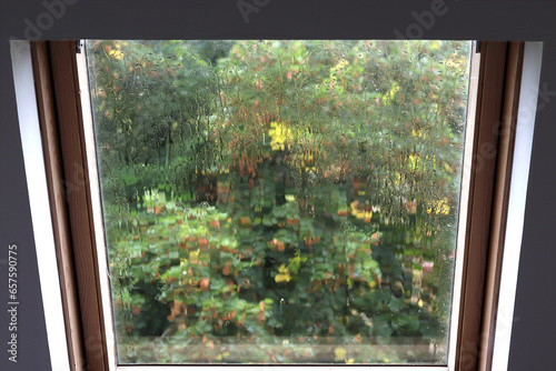 la pluie sur la vitre d'une fenêtre de toit donne un aspect abstrait au paysage