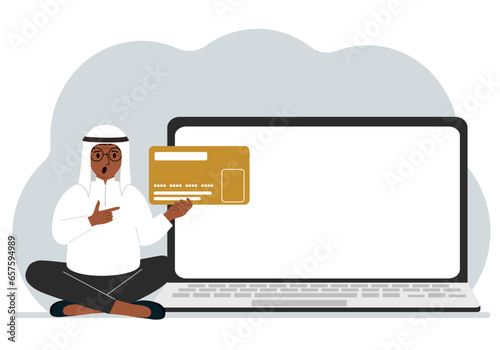 A man sits cross-legged and holds a large plastic card. Next to the man is a large laptop with space for text.