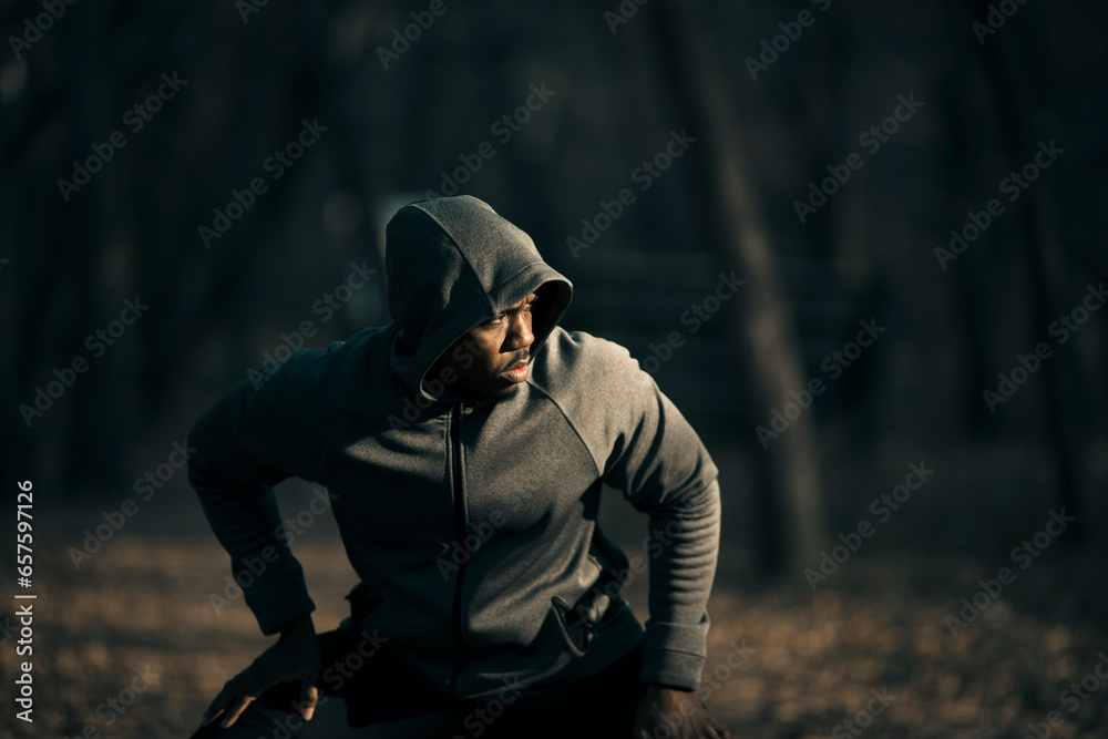 Young fit man stretching and warming up before a workout in a outdoor park Young fit man stretching and warming up before a workout in a outdoor park