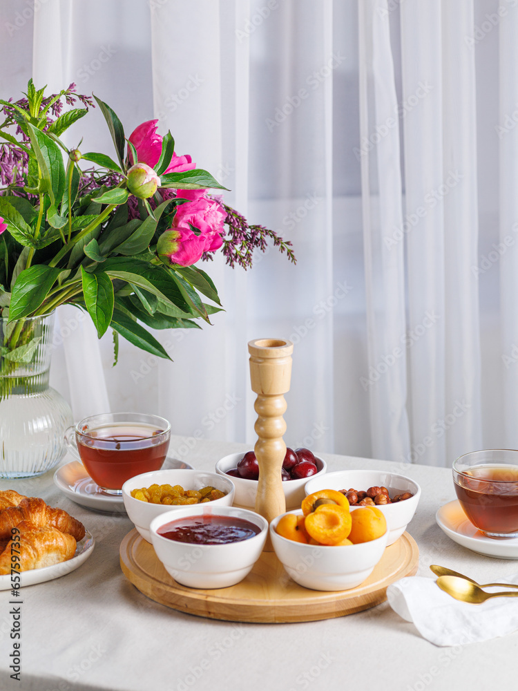 Fresh and bright continental breakfast table with jam, cheese, nuts and croissant. Vertical