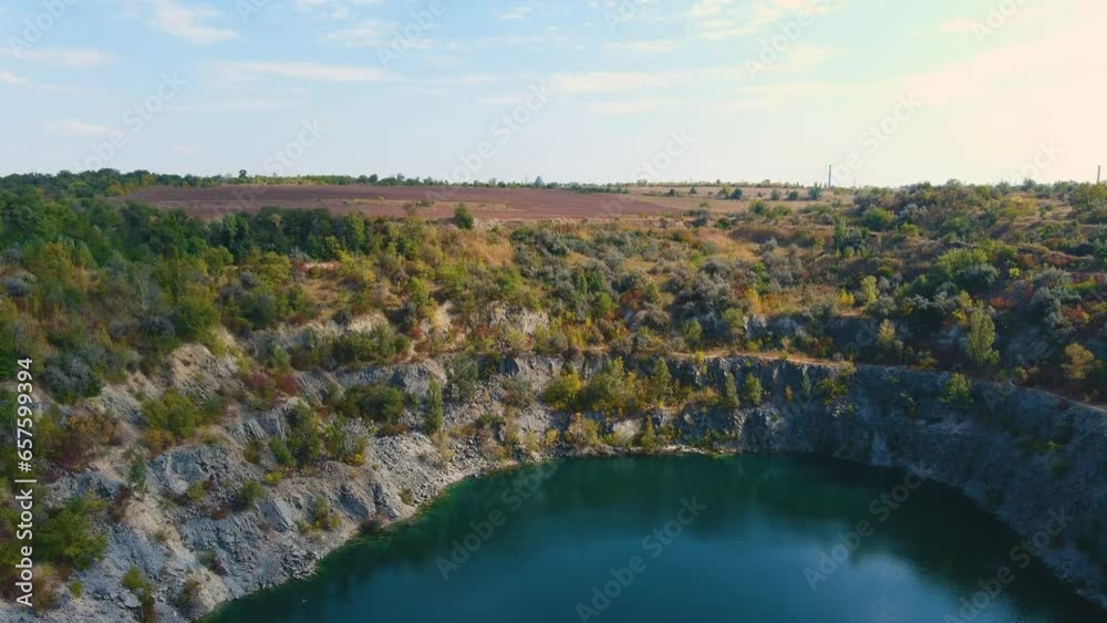 Top view of a flooded and abandoned granite quarry with clear turquoise water (camera moves up) Top view of a flooded and abandoned granite quarry with clear turquoise water (camera moves up)