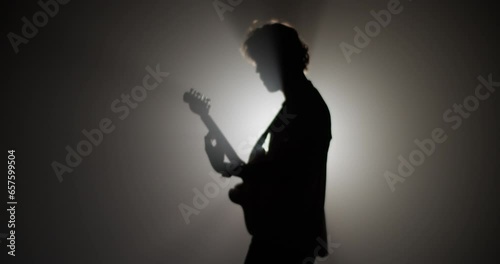 Silhouette of rock musician playing guitar against spotlight