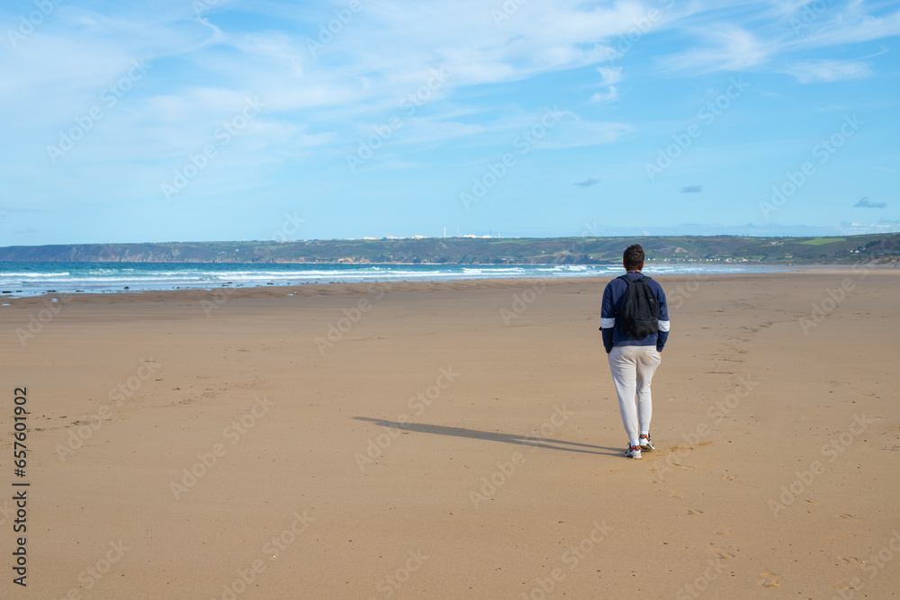 homme seul qui marche sur une grande plage de sable déserte
