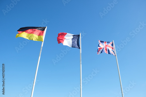 Flags of Germany, France, and Great Britain waving . Clear blue sky in the background 