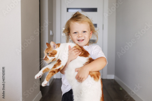 A little boy hugs his furry pet. Happy laughing child taking care of his domestic cat, feeding and playing with it