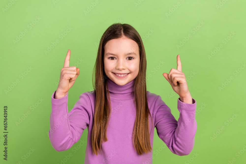 Portrait of nice schoolgirl with long hair dressed violet sweatshirt indicating at offer empty space isolated on green color background Portrait of nice schoolgirl with long hair dressed violet sweatshirt indicating at offer empty space isolated on green color background