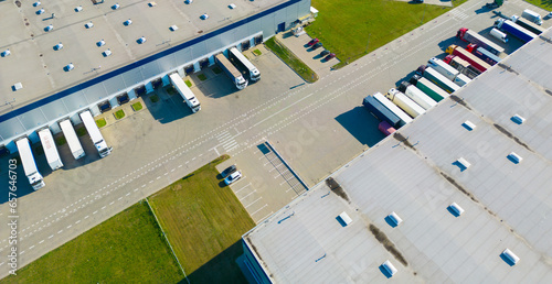 Fototapeta Naklejka Na Ścianę i Meble -  Aerial view of goods warehouse. Logistics center in industrial city zone from above. Aerial view of trucks loading at logistic center