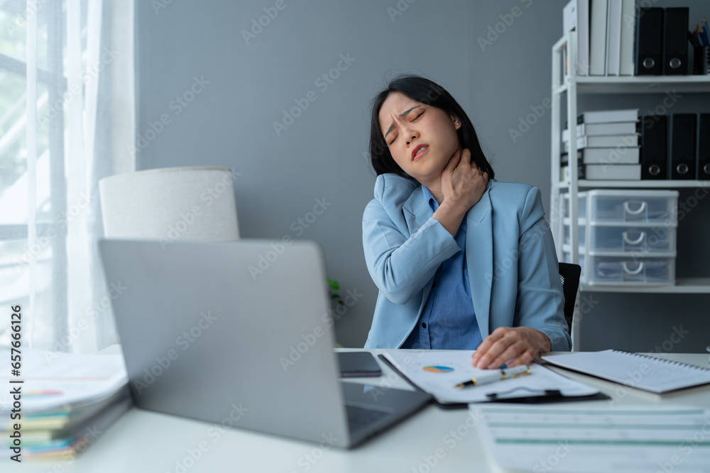 A young Asian businesswoman sits in a chair relieved from fatigue as she sits in the office with a happy smile at business success. A young Asian businesswoman sits in a chair relieved from fatigue as she sits in the office with a happy smile at business success.
