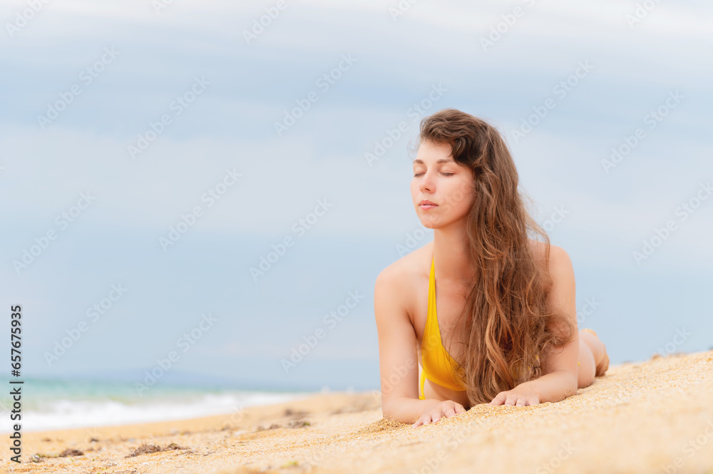 Beautiful woman with perfect body lies on sandy beach, wearing yellow bikini, sunbathing at beach resort, enjoying summer vacation Beautiful woman with perfect body lies on sandy beach, wearing yellow bikini, sunbathing at beach resort, enjoying summer vacation