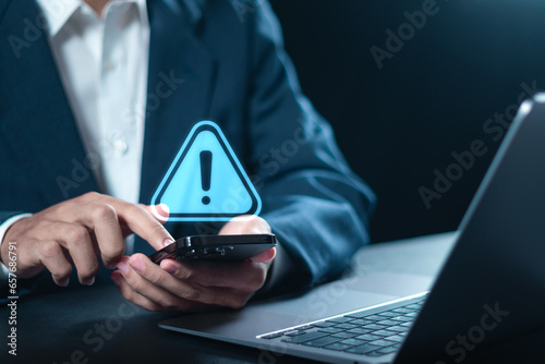 Maintenance concept. Businessman using smartphone with triangle caution warning sign for notification error. System failure and security issues.