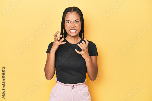 Young Indonesian woman on yellow studio backdrop upset screaming with tense hands.