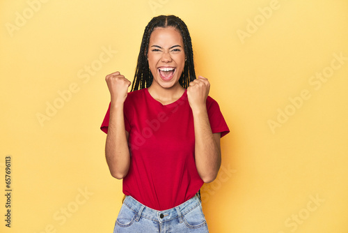 Young Indonesian woman on yellow studio backdrop cheering carefree and excited. Victory concept. photo