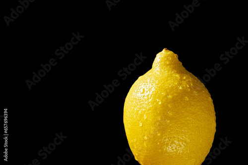 Close up of lemon with water droplets on black background