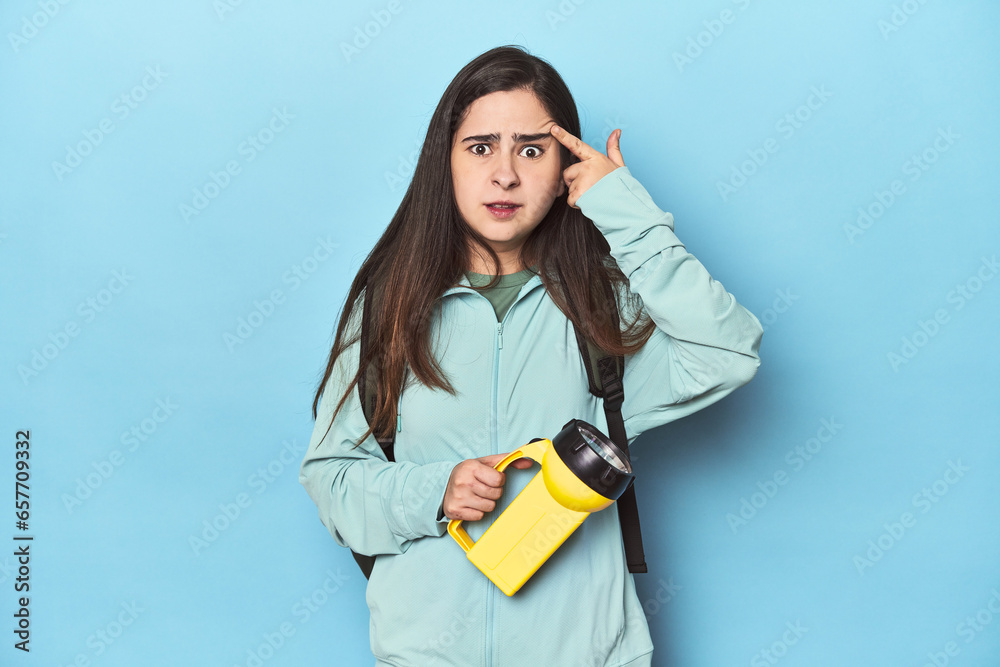 Adventurous woman with backpack on blue showing a disappointment gesture with forefinger. Adventurous woman with backpack on blue showing a disappointment gesture with forefinger.