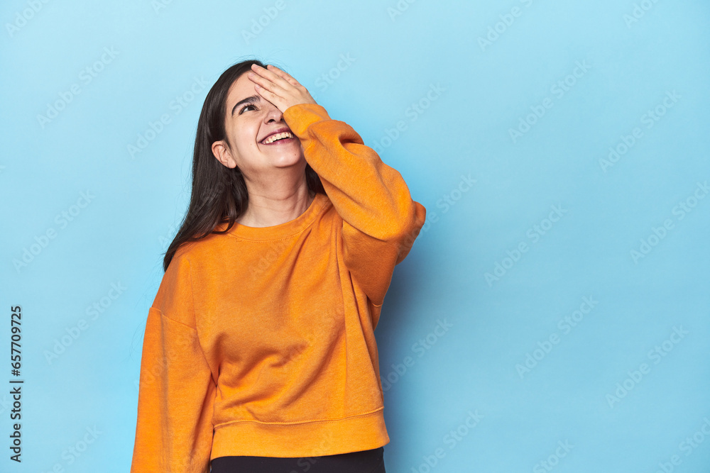 Young Caucasian woman on blue backdrop laughing happy, carefree, natural emotion. Young Caucasian woman on blue backdrop laughing happy, carefree, natural emotion.