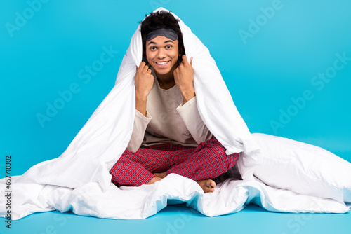 Full body portrait of positive nice person sit comfy bed covered blanket isolated on blue color background