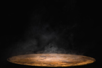 Empty old circular wooden table with smoke float up on dark background