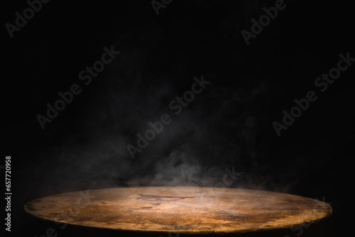 Empty old circular wooden table with smoke float up on dark background photo