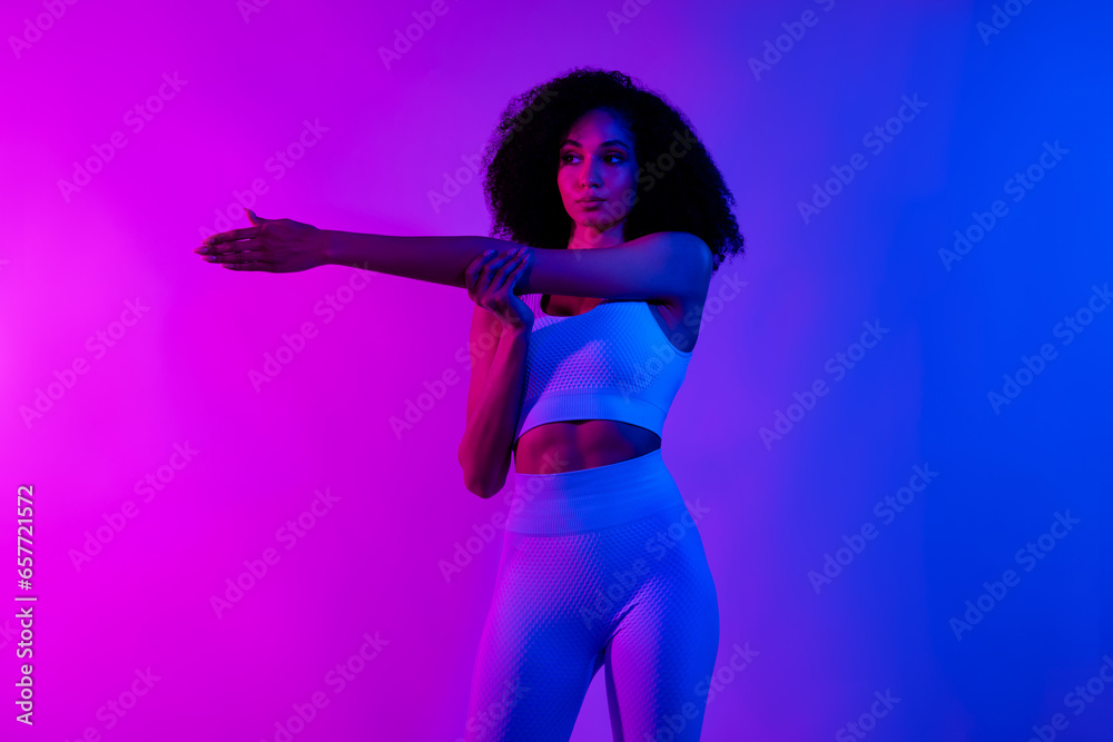 Portrait of gorgeous stunning fitness blogger lady stretching arm warm up isolated on colorful neon color background Portrait of gorgeous stunning fitness blogger lady stretching arm warm up isolated on colorful neon color background