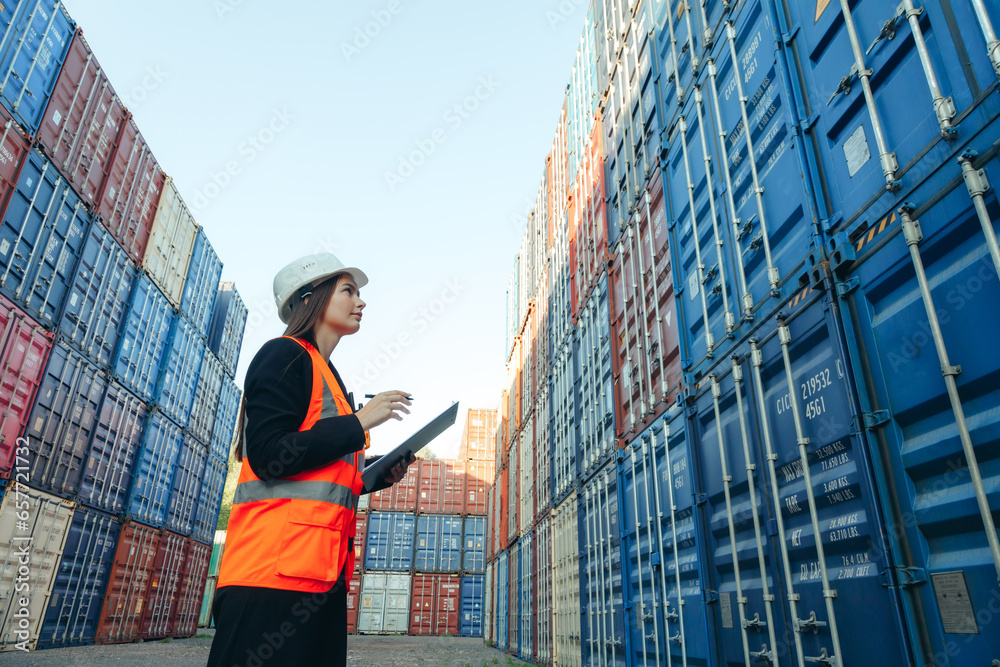 Fototapeta premium Woman engineer with Clip Folder in white helmet and vest working in container terminal port