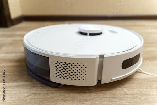 White robotic vacuum cleaner on linoleum floors smart cleaning technology. Selective focus photo