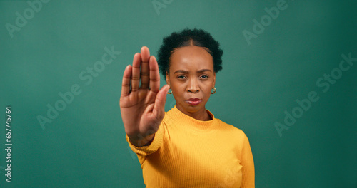 Foto Young Black woman holds up hand saying No, Stop, green studio background