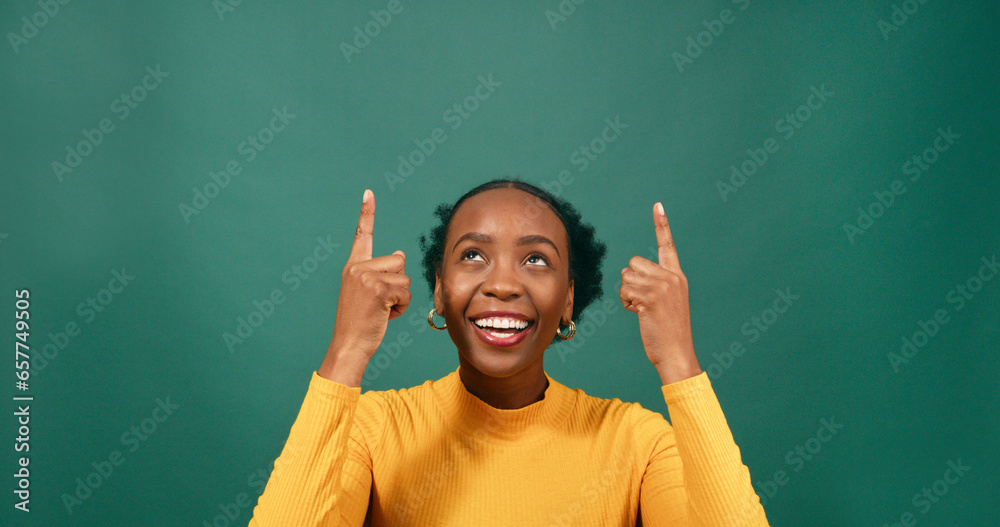 Beautiful Black woman pointing up at copy space, green studio background