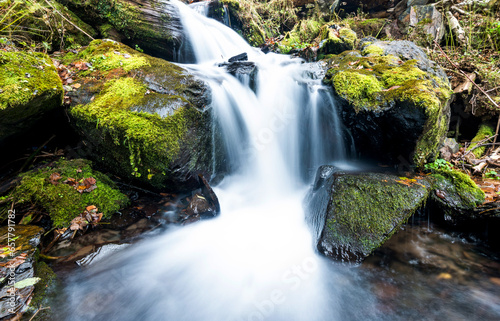 Blurred waterfall throughing mossy rocks
