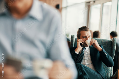 Mature businessman talking on his smartphone while enjoying a cup of coffee in a cafe