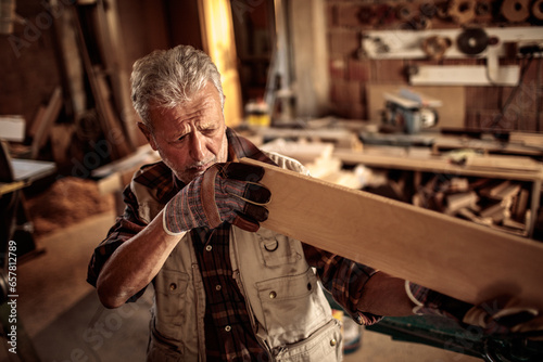 Fototapeta Naklejka Na Ścianę i Meble -  Senior male carpenter measuring wood in a carpentry shop