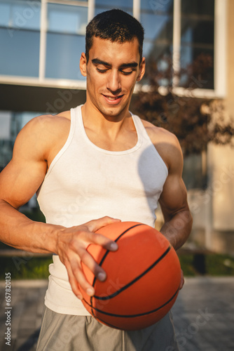 Portrait of strong athlete man hold basketball ball wear white a-shirt